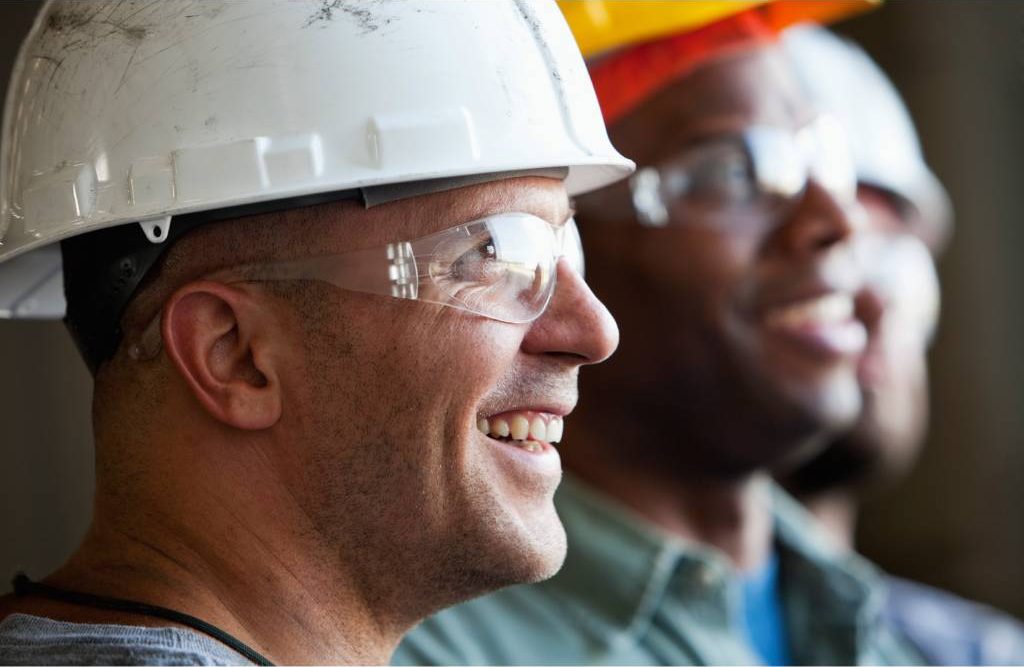 three men in hard hats and safety glasses smiling